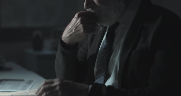 Nervous businessman checking stock market news on the newspaper