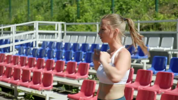 Young Fit Busty Woman with Ponytail in Sportswear Stretching at Sports Ground