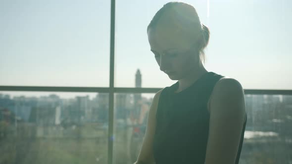 Attractive Young Boxer Putting on Gloves Standing Against Panoramic Window in Gym alt