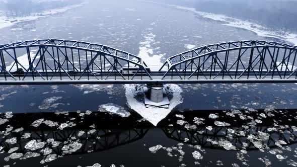 Snowy bridge over river with floe in winter alt