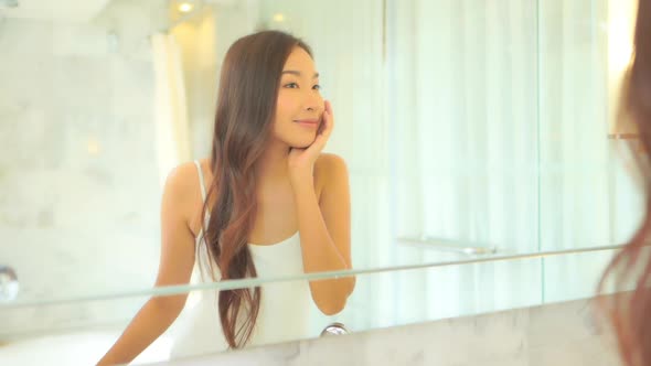 Young asian woman check her face on mirror alt