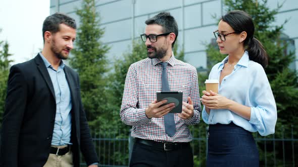 Businesspeople Talking Using Tablet Outside Near Office Center Discussing Business alt