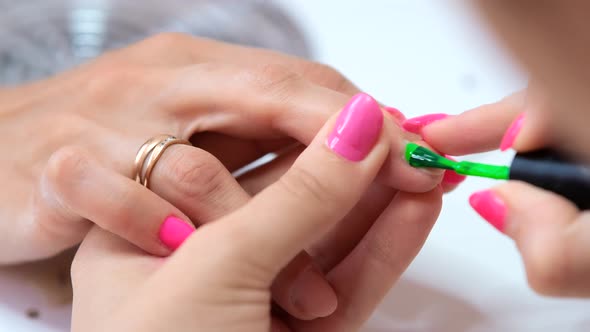 Close up woman hands in a nail salon receiving a manicure. Green nail Polish.  selective focus.