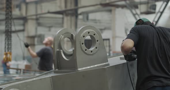 Factory Workers at Work Polishing the Parts of a Mud Gun Machine alt