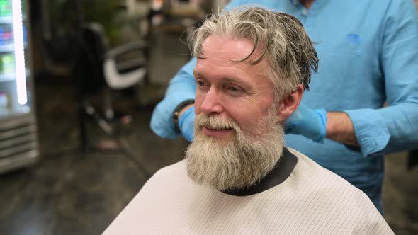 Overgrown gray-haired man waiting for a haircut in a barbershop alt