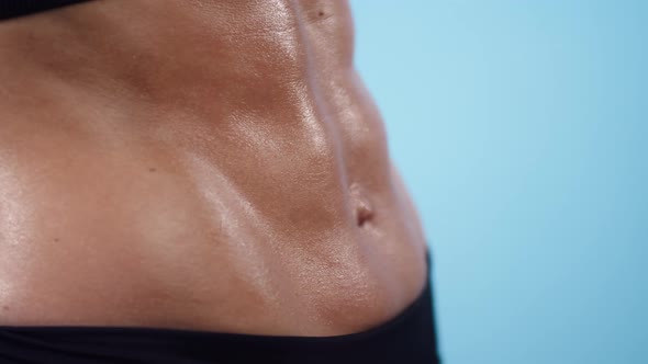 On Muscular Belly of a Woman Flows a Drop Sweat Closeup in the Studio alt