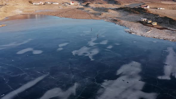 Drone Pilots Standing On Ice And Huts On Beach alt