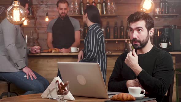 A Man Having an Online Call at His Laptop While Working in a Coffee Shop alt