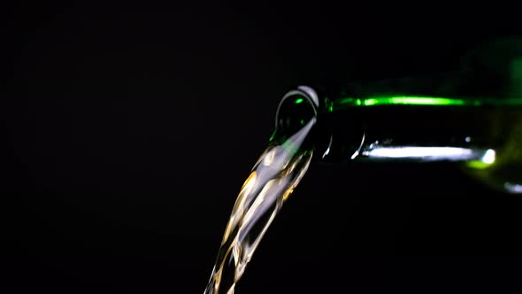 Stream of Beer Runs Through the Open Green Glass Bottle