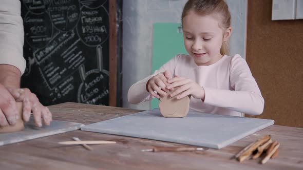 Attractive Little Girl Is Shaping and Preparing Clay with Help of Adult, Experienced Man.