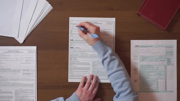 Man Filling In Individual Income Tax Return At Table