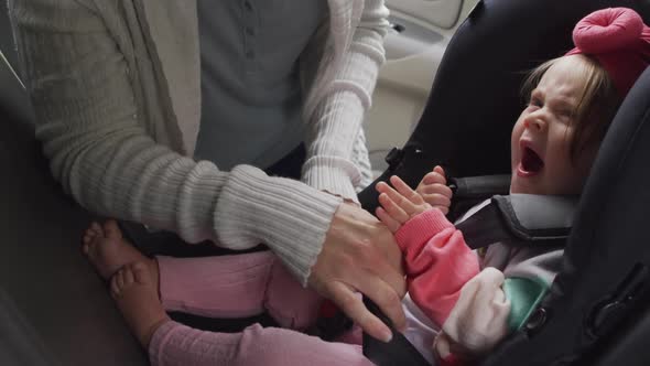 Mid section of caucasian mother keeping her baby in safety seat in the car alt