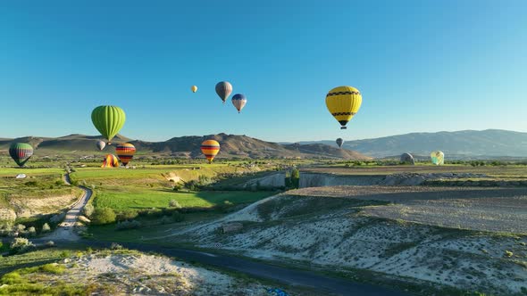 Hot air balloons fly over the mountainous landscape of Cappadocia, Turkey. alt