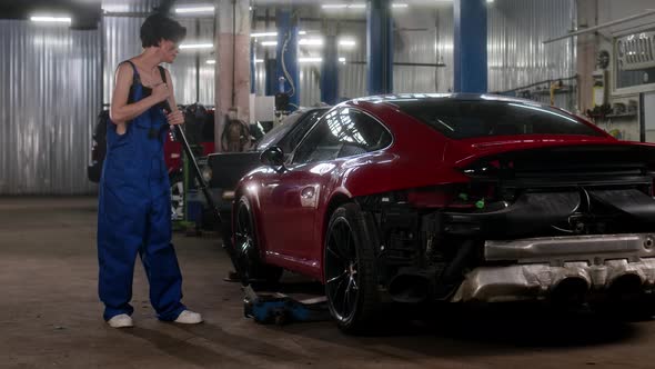 Woman Car Service Worker Approaches to Red Unrecognizable Sports Car and Raises It on Rolling Jack alt