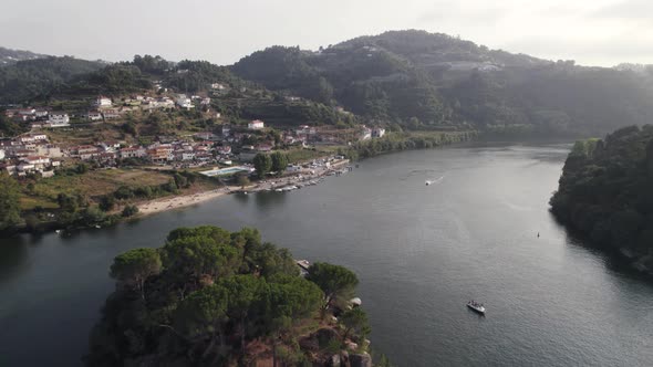 Aerial flying forward Douro river passing by small island, Ilha dos amores - Portugal alt