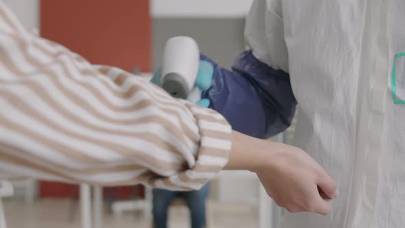 Unrecognizable Worker Using Contactless Thermometer alt