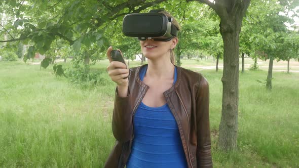 Young Sexy Woman In A Virtual Reality Helmet Uses A Virtual App In The Park