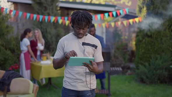 Young Focused African American Freelancer Using Video Chat on Tablet with Group of Relaxed alt