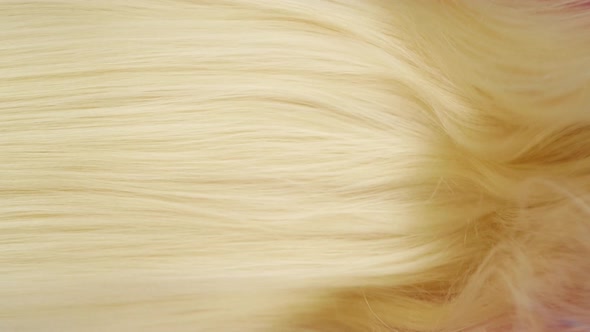 Slow motion of close-up of beautiful blond long smooth straight hair extension texture. alt