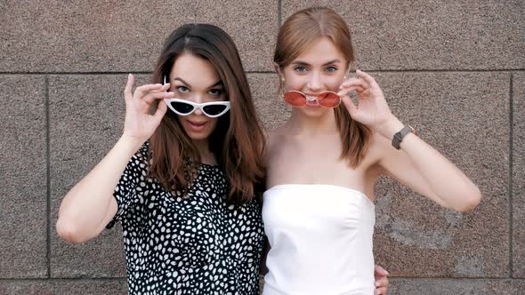 Portrait of two young beautiful smiling hipster girls in trendy summer clothes alt