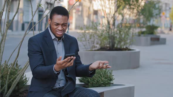 Mad Stressed Black Guy Holding Cellphone Annoyed with Error Spam Message Slow Stuck Broken alt