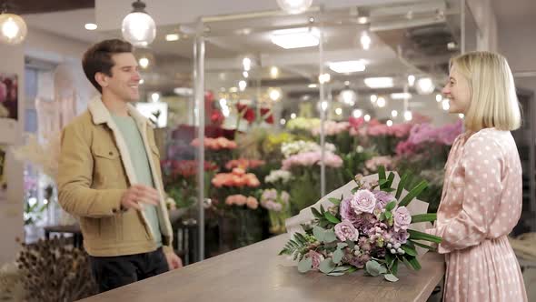 Girl Florist Gives A Bouquet To The Male Customer. Soft Focus. alt
