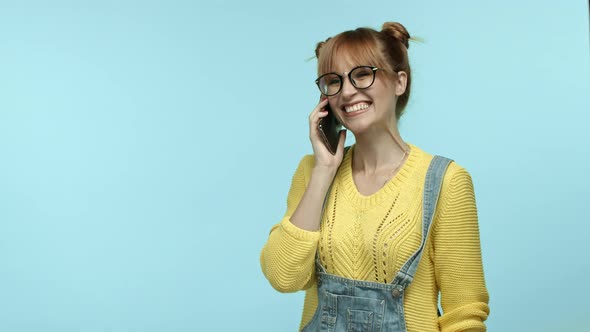 Cheerful Glamour Girl in Glasses and Overalls Talking on Phone Having Funny Conversation Calling a