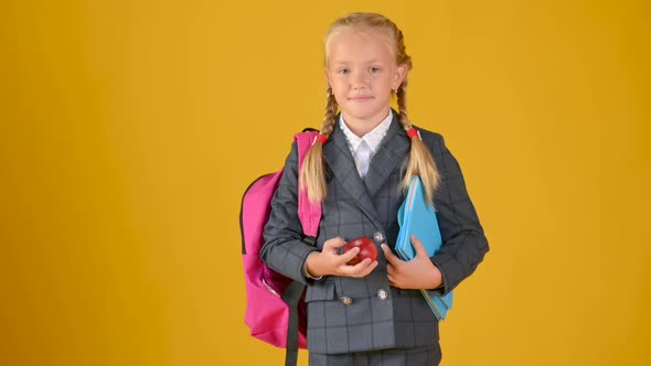Portrait of a teenager schoolgirl in a school uniform with books and an apple in her hands alt