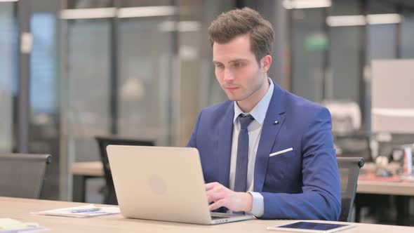 Businessman Shaking Head As No Sign While Using Laptop in Office alt