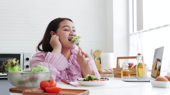 Happy overweight woman eating fresh salad with great pleasure