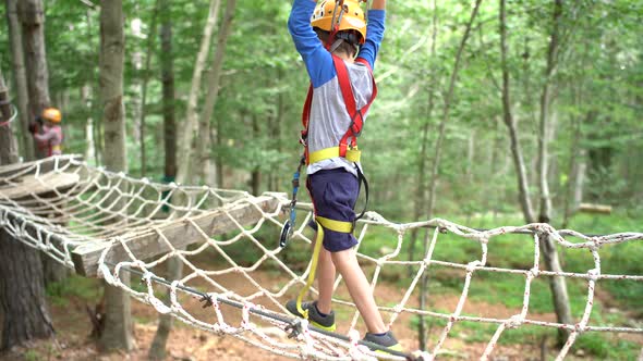 Boy Move on a Mesh Bridge  Holding on to a Safety Rope alt