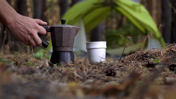 The Tourist's Hand Pours Aromatic Coffee Into a Mug From a Geyser Coffee Maker. alt