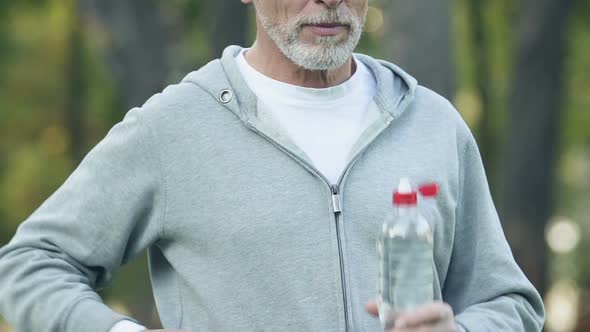 Mature Man Drinking Water Posing at Camera, Restoring Balance of Minerals alt