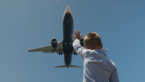 Child waving hand to the plane overhead