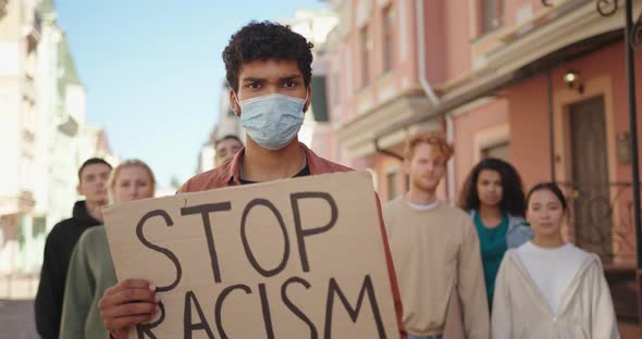 Mixed Race Man Leader at the Protest Showing Poster with Stop Racism Sign alt