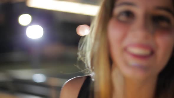 Teenage girl laughing outdoors at night, portrait