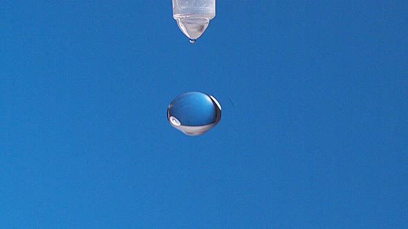 700721 Drop of Water falling against Blue background, Slow motion alt