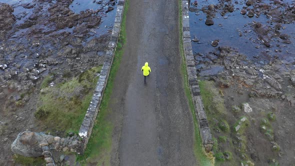 Aerial drone view of man hiking and crossing a bridge over a creek in Scotlan