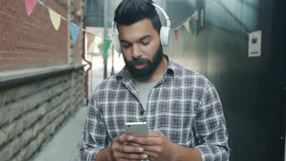 Slow Motion of Young Arab Listening to Music Outdoors Using Smartphone and Headphones alt