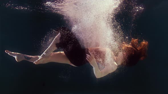 Woman in a Swimsuit and a Black Skirt Swims in the Water Waving Arms and Legs