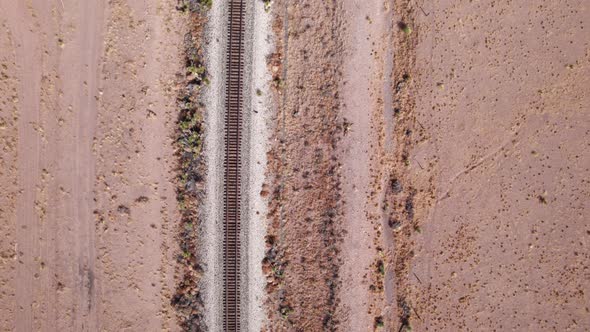 Drone shot looking down on railroad tracks in the desert on a sunny day alt
