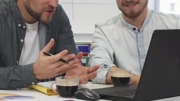 Cropped Shot of Two Male Business Colleagues Having Coffee Discussing Work