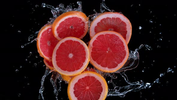 Super Slow Motion Shot of Rotating Exploded Grapefruit Slices and Water on Black at 1000Fps alt