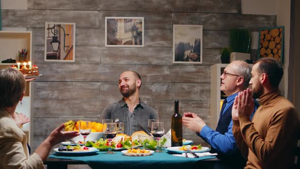 Young Man Blowing Candles From the Cake, Celebrating His Birtday with Family and Friends alt