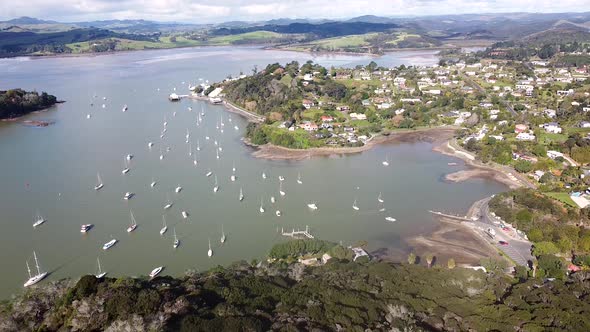 A lowering aerial drone shot of Mangonui town, harbour and boats on the Doubtless Bay in Northland, alt