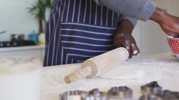 Hands of african american man using flour, preparing dough in kitchen alt