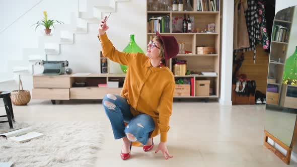 adult woman indoor at home using smart phone taking selfie alt