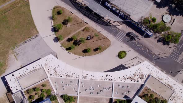 Aerial shot following a bike on the street while a tram stops at the tram stop. alt