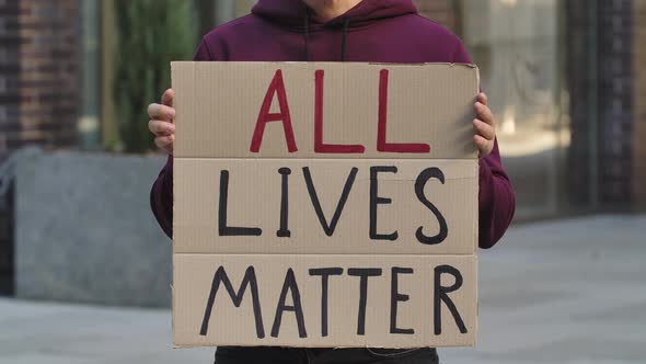 ALL LIVES MATTER on a Cardboard Poster in the Hands of Male Protester Activist. Closeup of Poster alt