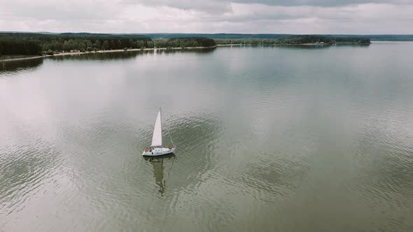 The Drone Slowly Flies Over a Sailing Boat in the Lake